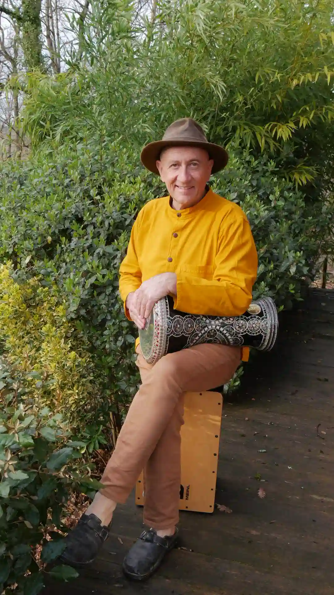 Jean-François est assis sur un cajon et tioent une derbouka